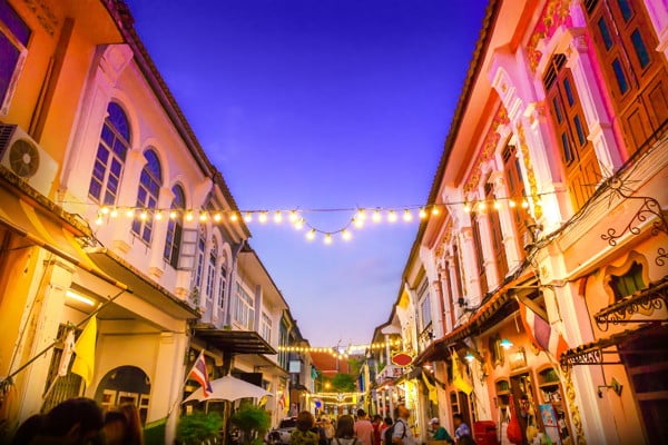 a beautiful sunset night market shot with people walking through the market stalls and lights glistening above