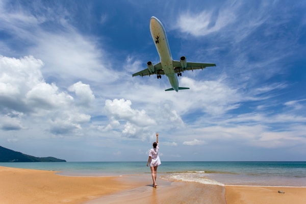 a woman celebrates enthusiastically as a plane flies low overhead